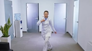 Modern bir hastane koridorunda kameranın önünde dans eden bir grup olgun, genç doktor ve hemşire heyecanlanıyor.