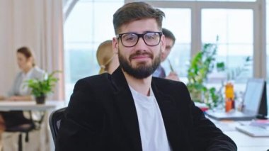 Eğitim seminerinde gözlüklü karizmatik bir adam masada oturmuş kameraya bakıyordu.