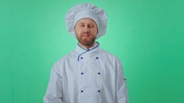 Yeşil arka plan iyi görünümlü fırıncı, elleri kameranın önünde el hareketleriyle büyük benzerlikler gösteriyor ve mutlu bir yüzü var. ARRI Alexa Mini 'de çekilen
