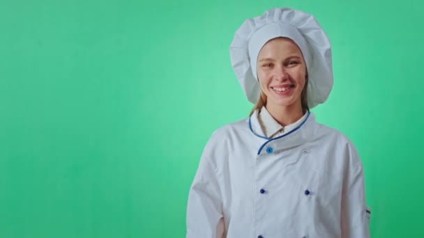 Baker signora molto carismatico con un grande sorriso all'interno in un grande studio verde lei gesticolando e mostrando alcuni con mano poi guardando direttamente alla fotocamera. Girato su ARRI Alexa Mini — Video Stock