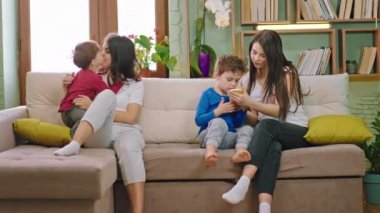 Evde, oturma odasında iki anne ve çocukları sohbet ederken zaman geçiriyorlar ve çocuklar da oyun oynamak için akıllı telefonları kullanıyorlar. ARRI Alexa Mini 'de çekilen