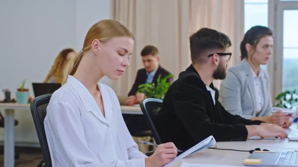 Le matin devant la caméra charismatique belle dame mangeoire de bureau avec un grand sourire au séminaire de formation, elle prend quelques notes dans son carnet puis regarde vers la caméra et souriant — Video