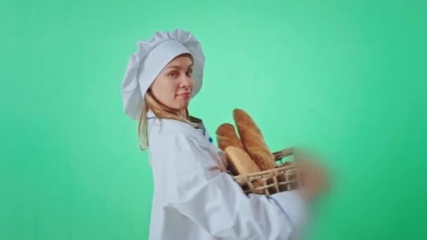 Chroma key studio hermosa panadera señora bailando con una cesta de pan fresco ella en el tiempo delante de la cámara ella tiene una gran sonrisa — Vídeos de Stock