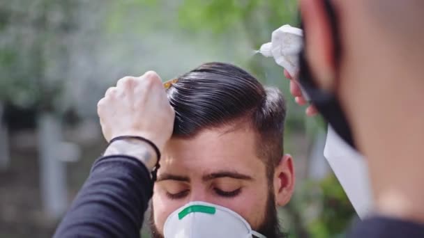 Primer plano de la cámara barbero hombre hacer un corte de pelo a su amigo en el jardín en casa en la cuarentena Coronavirus 2019 — Vídeos de Stock