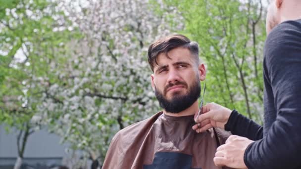 Evde bahçedeki adamın profesyonel bir saçı var. Profesyonel makası kullanarak sakalını kesiyor. — Stok video