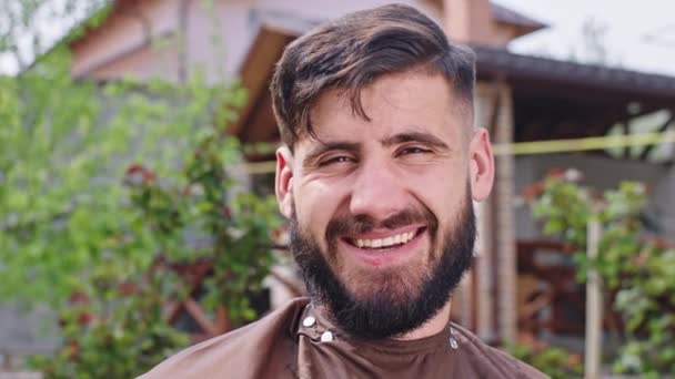 Attraktiver Typ mit einem breiten Lächeln nach dem Haarschnitt im heimischen Garten, der glücklich und aufgeregt in die Kamera blickt — Stockvideo