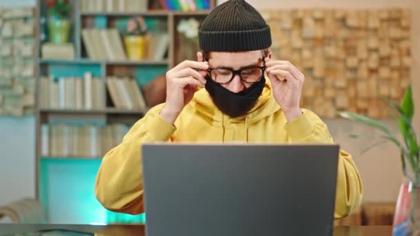 I karanteneformens hjemmekontor. En fyr som jobber på nettet fra laptopen, med beskyttelsesmaske i ansiktet, Covid-19 karantene Kina. – stockvideo