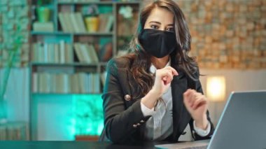 İş yerindeki karantina işindeki kadın dizüstü bilgisayarla çalışmaya başlamanın ne kadar doğru olduğunu gösteriyordu. Koruyucu bir maske takıyordu. Bir el dezenfekte edilmiş jel kullanıyordu.