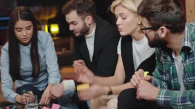 Modern bir kütüphanede sınıf projesinde birlikte çalışan harika görünümlü bir grup öğrenci bilgiyi analiz ediyorlar. Bazıları çok konsantre olamıyor..