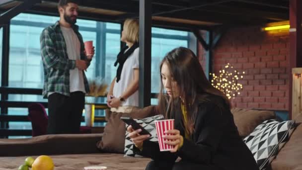 Break time in a modern office studio multiethnic workers Japanese lady take selfies on the sofa and drink some coffee other workers chatting with other — Vídeos de Stock