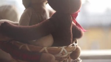 Açık pencerenin önündeki pencere pervazında iki oyuncak ayı ve rüzgarla bir kurdele savruluyor.