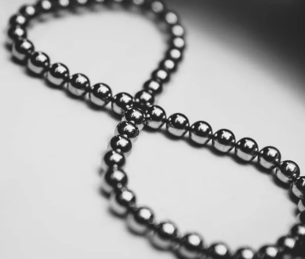 Black beads are stacked in a sign of infinity on a white background. Puzzle and constructor of magnetic balls for adults and children. Stunt. A toy. Accessory.