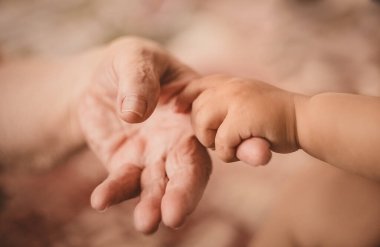 Küçük bir çocuk yaşlı birinin parmağını çeker.