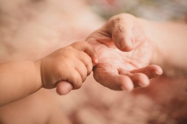 Çocuğun küçük eli yaşlı kadının parmağını sarar.