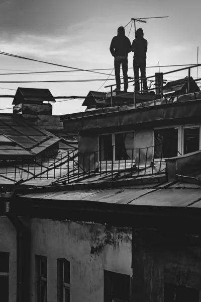 傍晚时分 有两个人站在一座房子的屋顶上 望着天空 — 图库照片