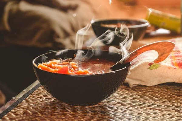 Sıcak borş ve ahşap kaşıklı siyah tabak.