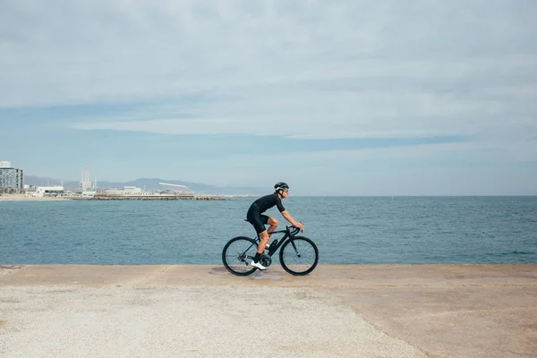 Ciclista masculino profesional cabalgando cerca del mar — Foto de Stock