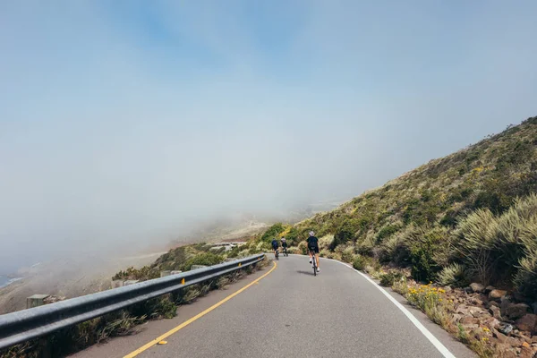 Grupo de ciclistas descendiendo por carretera ventosa — Foto de Stock