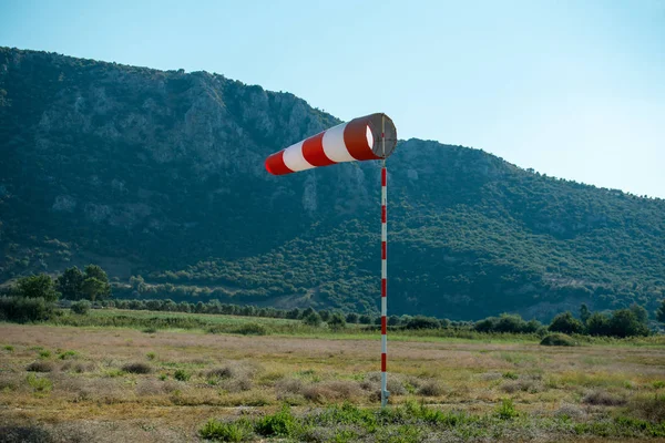 Yatay olarak uçan yüksek rüzgar nedeniyle (rüzgar vane) Rüzgar gülü. Mavi gökyüzü ve arka planda yüksek dağlar.