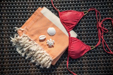 Düz kavramı yaz aksesuar beyaz ve turuncu Türk havlu, kırmızı bikini üst ve beyaz deniz kabuklarını rattan tembel üzerinde yatıyordu.