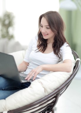 Otururken dizüstü bilgisayarda çalışan güzel genç gülümseyen kadın