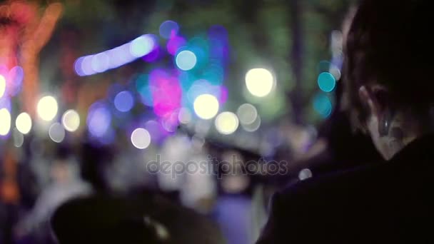 El tipo toca la batería en el parque nocturno de la ciudad, contra el telón de fondo de luces de colores . — Vídeos de Stock