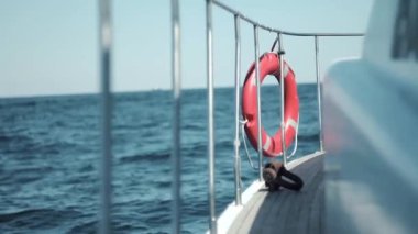 Beyaz tahta yat, denizdeki dalgalar üzerinde sallanan kapatın. Kırmızı lifebuoy korkuluk üzerinde asılı