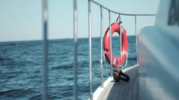 Embarque yate blanco, balanceándose sobre las olas en el mar de cerca. En la baranda cuelga una boya salvavidas roja — Vídeos de Stock