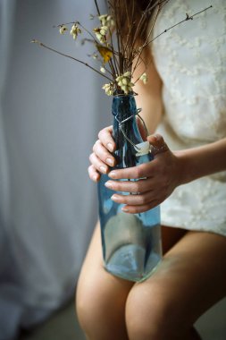 Mavi şişe bir kız elinde kuru çiçekler ile yakın çekim