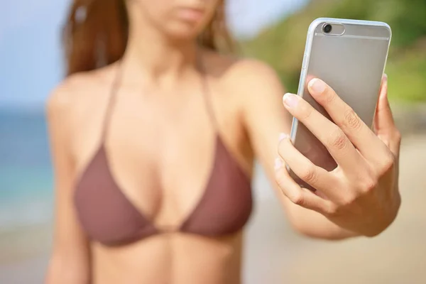 Женщина в бикини с помощью смартфона — стоковое фото