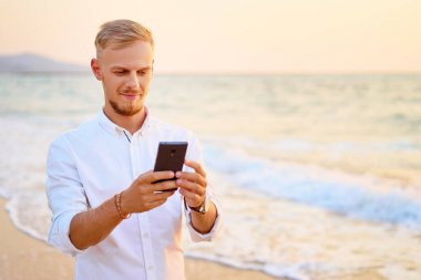 Deniz kıyısında Smartphone kullanan adam