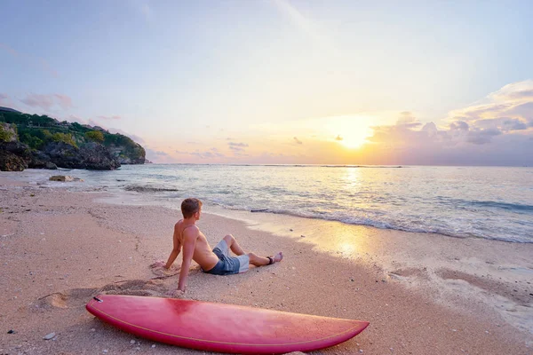 Homem sentado com prancha de surf — Fotografia de Stock
