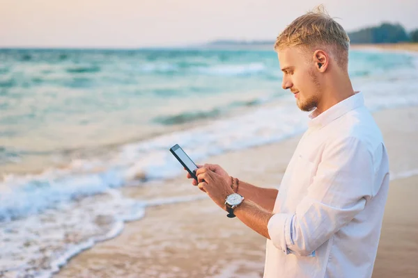 Ο άνθρωπος χρησιμοποιώντας smartphone στην ακτή θάλασσας — Φωτογραφία Αρχείου