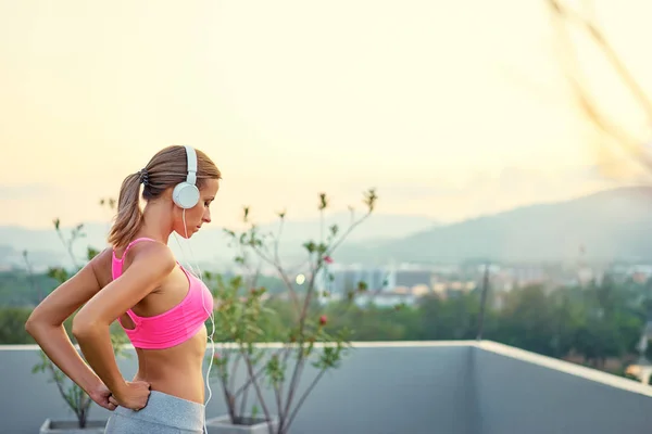 Woman in headphones stretching outdoor — Stock Photo, Image