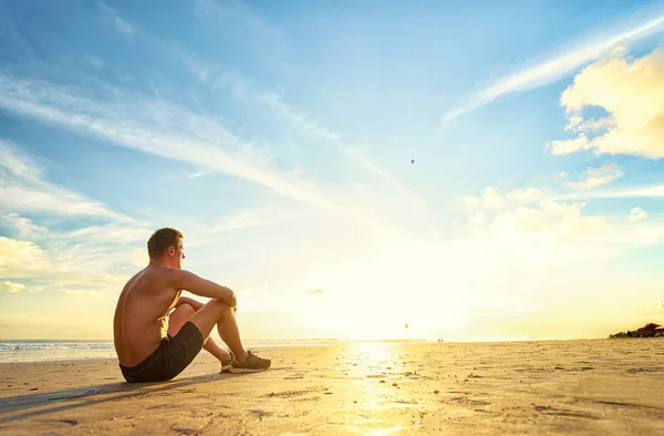 Izmos ember ül a strandon — Stock Fotó