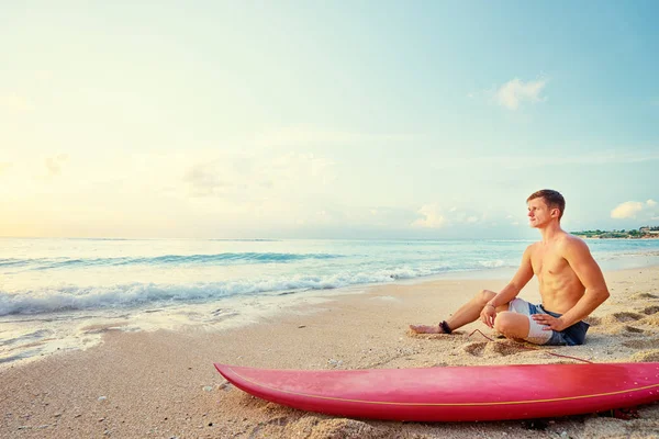 Homem sentado com prancha de surf — Fotografia de Stock