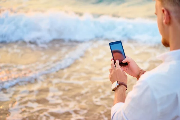 Hombre usando teléfono inteligente en la orilla del mar — Foto de Stock