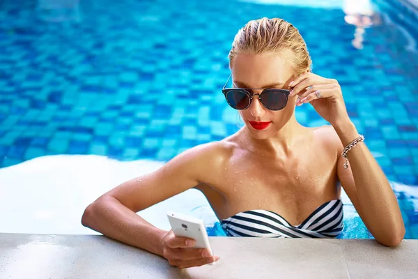 Mujer usando smartphone en la piscina — Foto de Stock