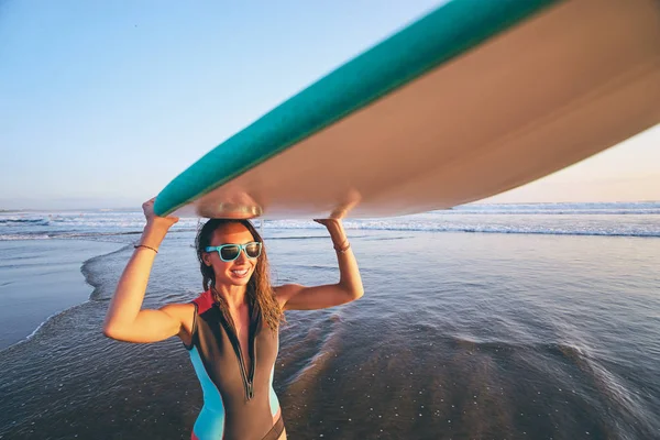 Mujer joven llevando tabla de surf — Foto de Stock