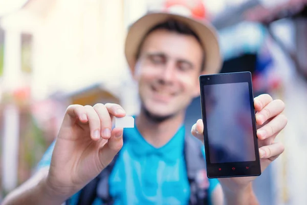 Junger Reisender zeigt Sim-Karte — Stockfoto