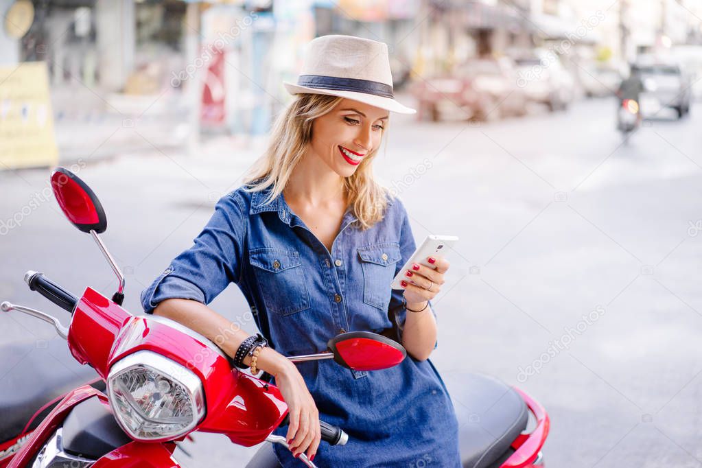 Young woman in hat using smartphone 