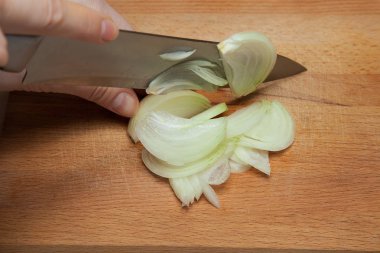 Kız, tahtadaki tembel lahana rulolarını ve köfteleri bıçakla hazırlamak için yayı kesiyor.