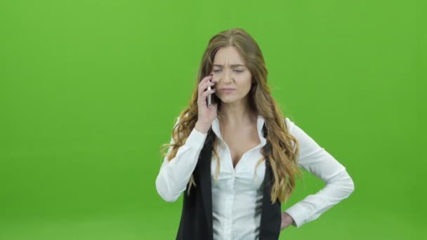 Una joven sobre un fondo verde con desagrado en el teléfono — Vídeos de Stock