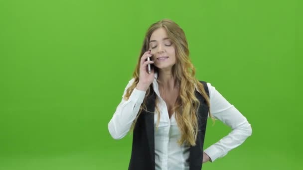 Młoda dziewczyna na zielonym tle z niezadowoleniem w telefonie — Wideo stockowe