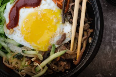 Kore yemeği bibimbap 'ı. Üst görünüm kapalı. Kore çubukları yakınlarda..