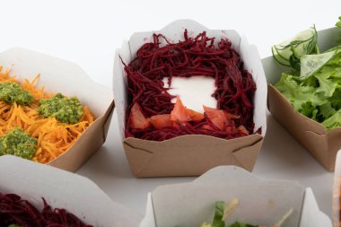 Karton tabaklarda yemeye hazır vejetaryenler ve çiğ gurmeler için farklı salatalar.