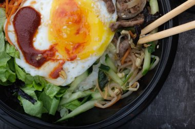 Kore yemeği bibimbap 'ı. Üst görünüm kapalı. Kore çubukları yakınlarda..