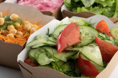 Karton tabaklarda yemeye hazır vejetaryenler ve çiğ gurmeler için farklı salatalar.