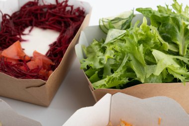 Karton tabaklarda yemeye hazır vejetaryenler ve çiğ gurmeler için farklı salatalar.