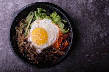 Kore yemeği bibimbap 'ı. Üst görünüm kapalı. Kore çubukları yakınlarda..